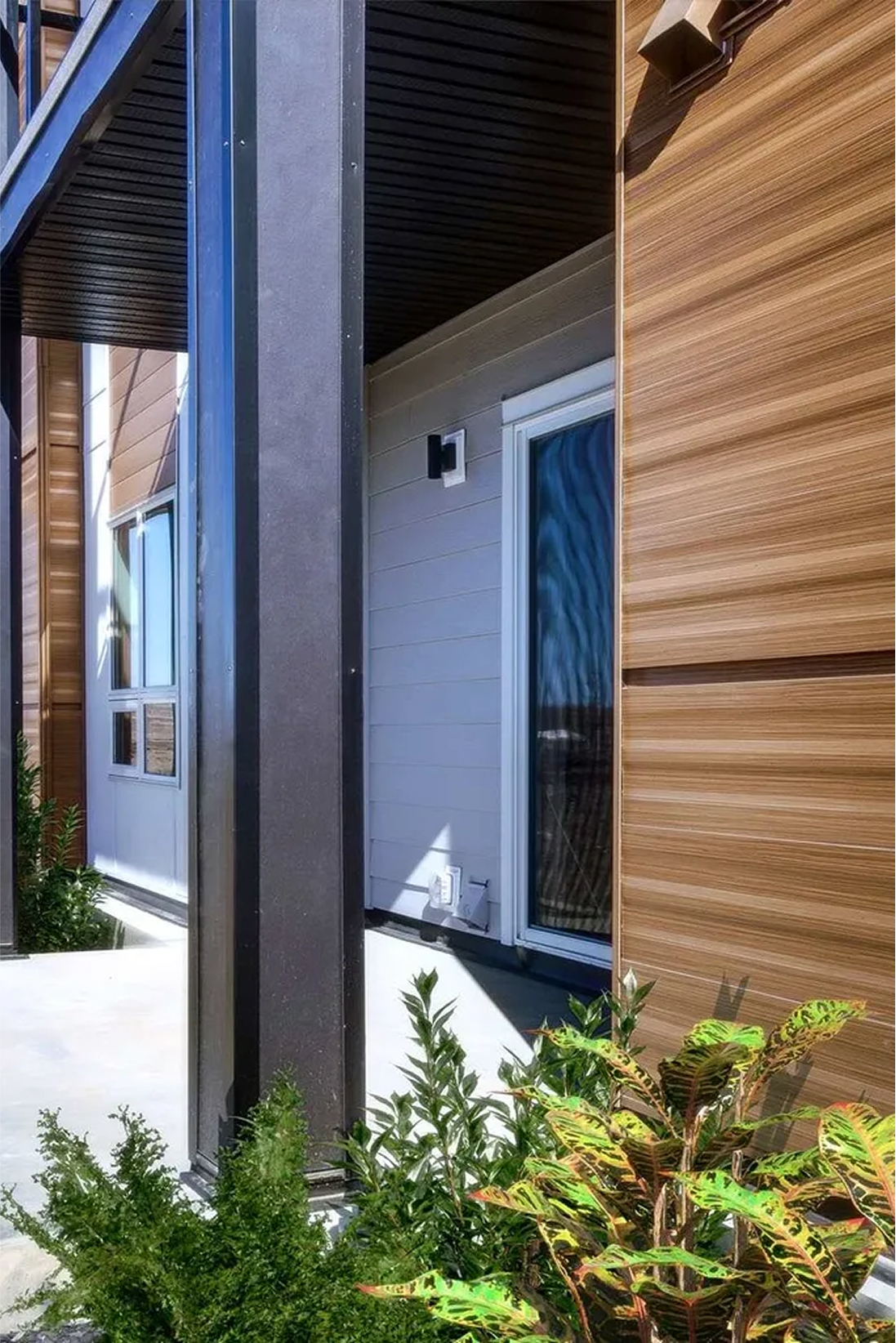 Close-up of black and white multi-family apartment exterior with wood accents, highlighting modern siding and design details.