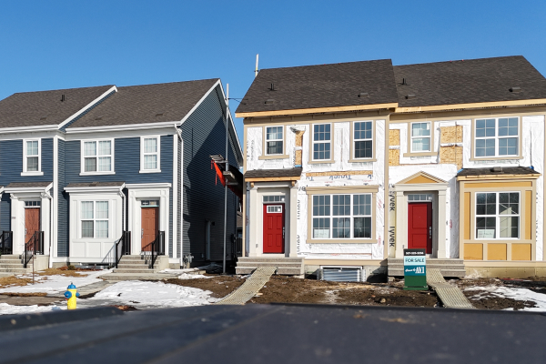 Multi-family units under construction, showing building framework and exterior preparation for siding installation.