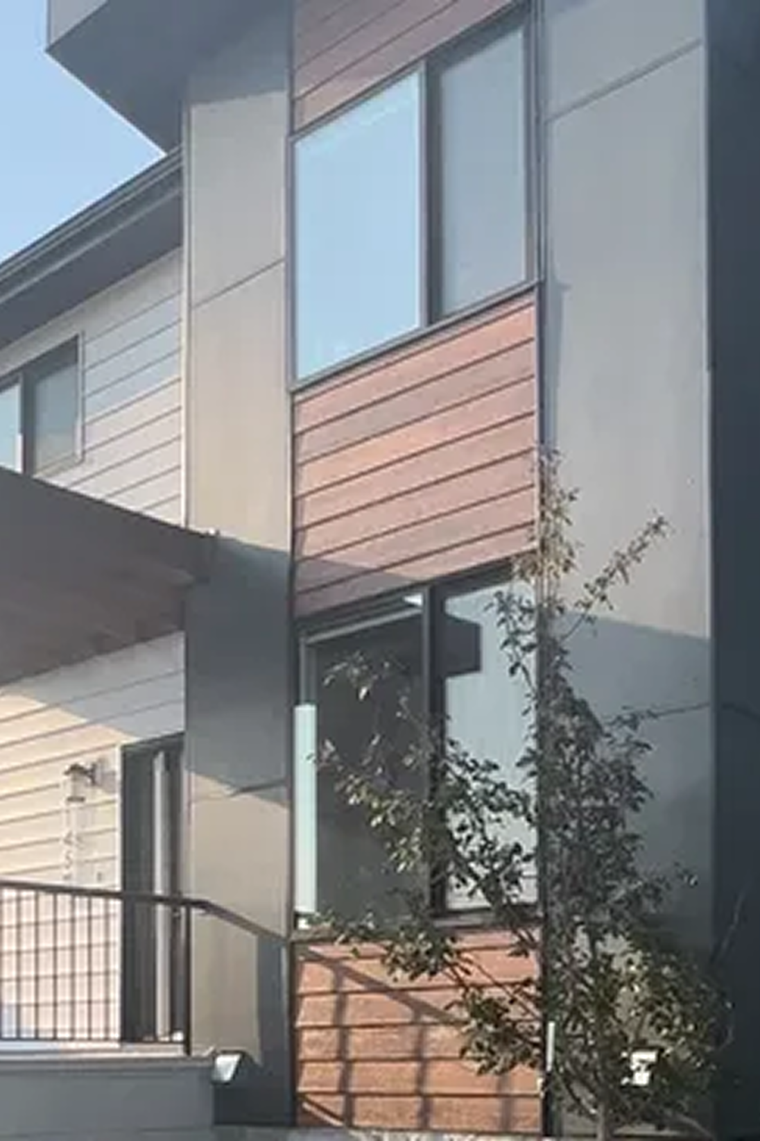 Modern multi-family building with black siding and wood accents, showcasing exterior design styles offered by Calgary’s Great Albertan Exteriors.